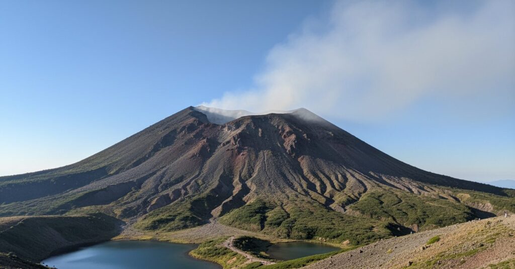 北海道の雌阿寒岳から白い噴気が上がる風景。噴火警戒レベル2への引き上げを伝える画像。