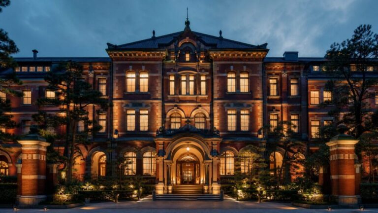 An elegant red-brick historic prison building transformed into a luxury hotel under warm evening lights.